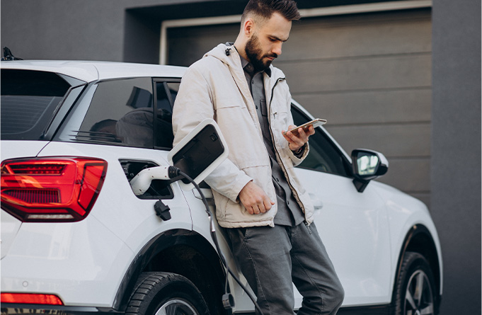 Man checking his phone while charging his car